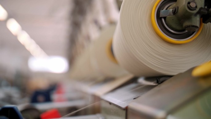 近距离的纱线线轴。纺织厂设备。纺织工厂。纺纱生产。纱线制作工艺。线生产。