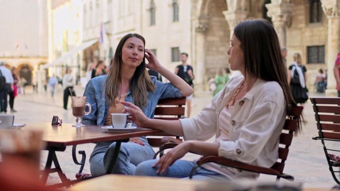 两个女性朋友在杜布罗夫尼克的路边咖啡馆喝咖啡
