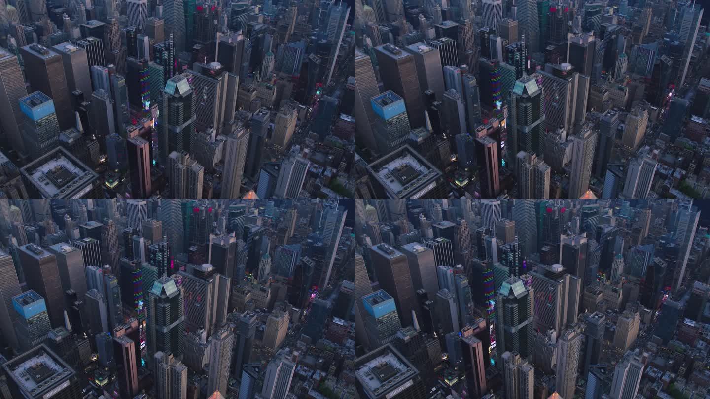 高角度空中直升机镜头在曼哈顿中城摩天大楼的城市景观与灯光从窗户，照明，广告牌。美丽的夜晚，温暖的夕阳