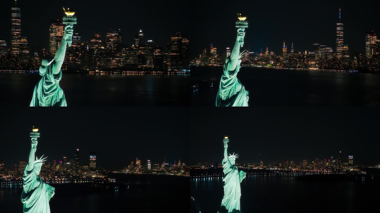 电影直升机在夜晚经过自由女神像。被照亮的罗马女神手持火炬的近距离全景航拍镜头。地标性的纽约纪念碑和曼
