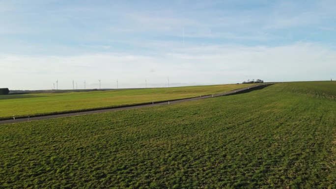 在冬天一个阳光明媚的日子里，无人机飞过乡村的草地，一直飞到公路上