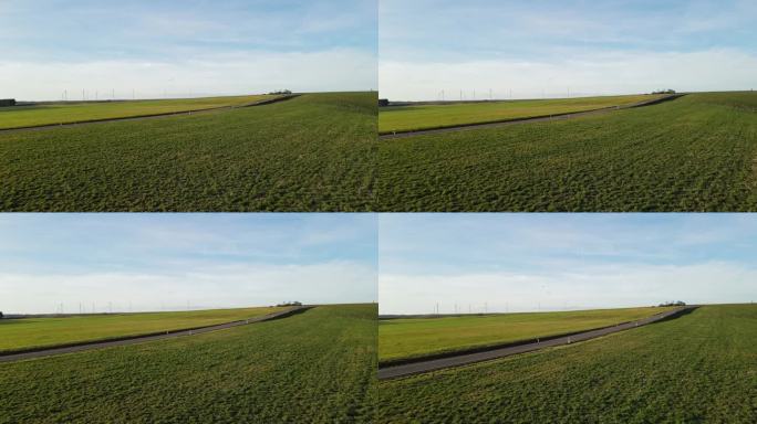 在冬天一个阳光明媚的日子里，无人机飞过乡村的草地，一直飞到公路上