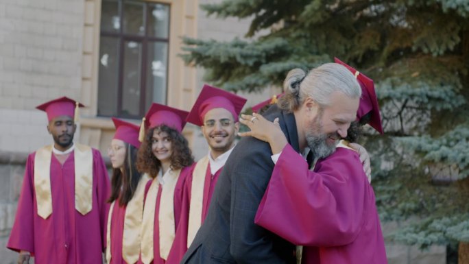 慢镜头的大学教授祝贺不同群体的学生毕业日在校园握手拥抱
