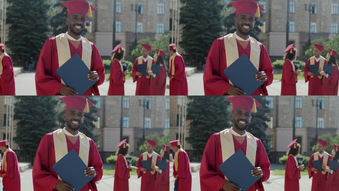 一个成功的非裔美国人的慢动作肖像，他穿着毕业袍，戴着毕业帽，站在校园里拿着毕业证书