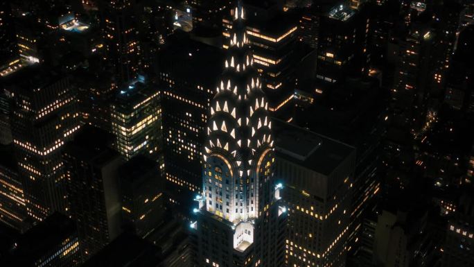 曼哈顿商业区空中夜景。装饰艺术办公楼楼顶塔的近景弧线镜头，楼顶塔尖上的灯光在窗户上工作