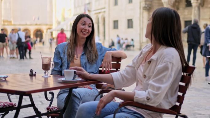两个女性朋友在杜布罗夫尼克的路边咖啡馆喝咖啡