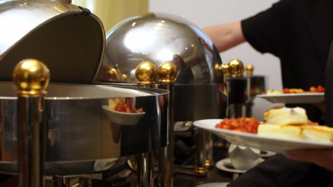 在一家高档酒店的自助服务队伍里，一群人从自助餐中倒出热而美味的食物。商务会议或在酒店休闲。