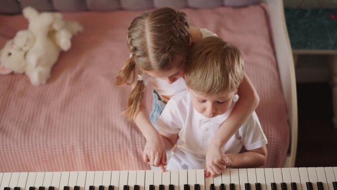 扎着辫子的女孩和哥哥一起弹钢琴