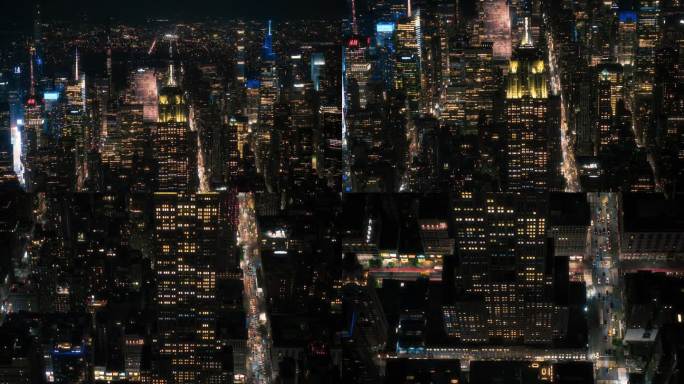 纽约市商业中心。著名的装饰艺术摩天大楼夜间航拍画面。直升机俯瞰帝国大厦，街道和大道上的汽车