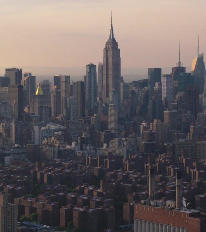 垂直屏幕:日落时的纽约市天际线。直升机航拍画面。帝国大厦与其他城市地标和摩天大楼。现代混凝土丛林建筑