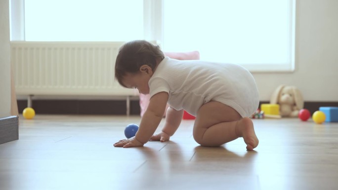 可爱的小女孩，蹒跚学步，早上爬到家里的地板上玩玩具。顽皮、健康、漂亮的宝宝
