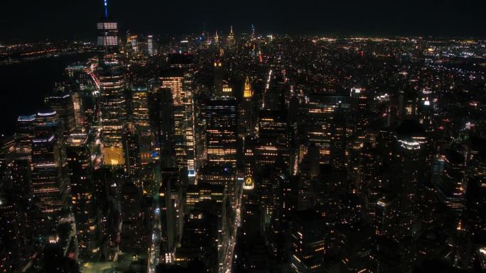 纽约曼哈顿大道航拍夜景，商业和住宅建筑屋顶，汽车和商用车辆夜间行驶。直升机查看一条笔直的道路与交通