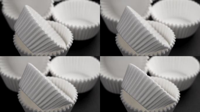 纸杯蛋糕松饼瓦楞纸模具。空的白色厨房工具，黑色背景上的甜点。旋转