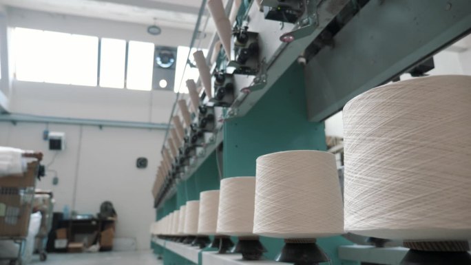 纺织工厂。纱线制作工艺。线生产。纺纱生产。纺织厂设备。近距离的纱线线轴。