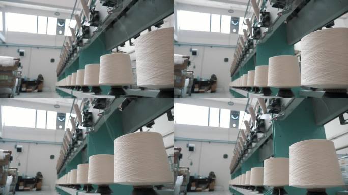 纺织工厂。纱线制作工艺。线生产。纺纱生产。纺织厂设备。近距离的纱线线轴。