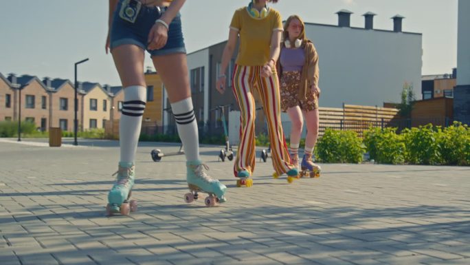 三个快乐的女孩穿着旱冰鞋在公园里开始滑冰