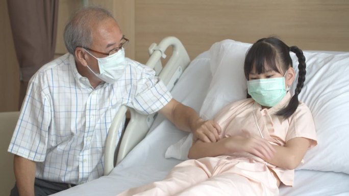 戴着口罩的亚洲老人试图和一个生病的小女孩说话。
