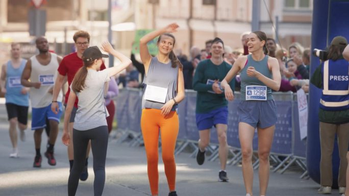 妇女支持妇女:参加马拉松比赛的快乐女选手肖像。一群朋友一起庆祝，互相祝贺越过终点线