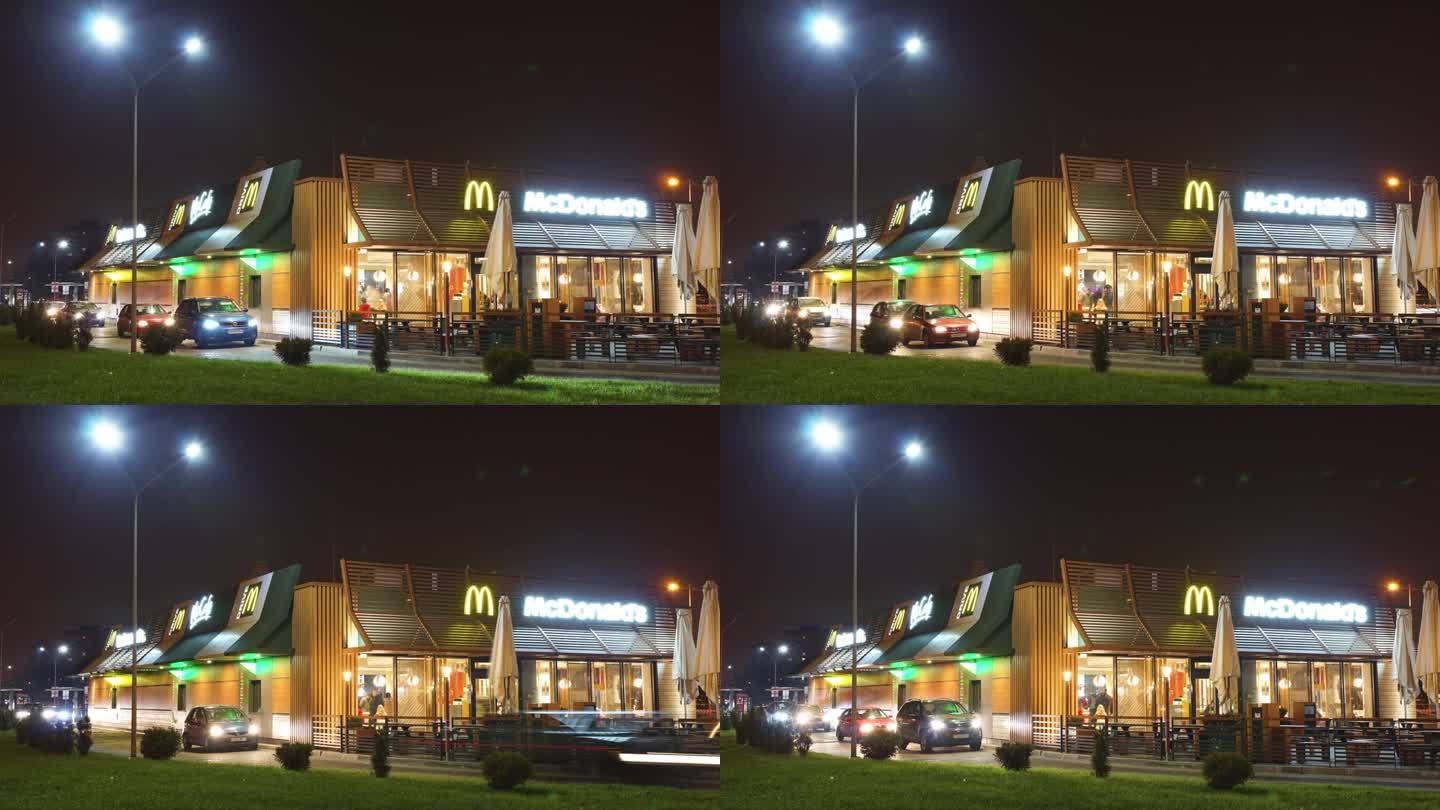 麦当劳快餐店夜间延时拍摄。汽车依次驶来吃快餐。