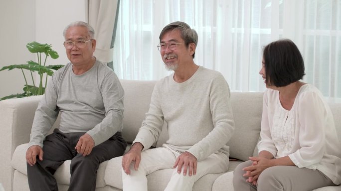 一群快乐的亚洲老人坐在沙发上谈论有趣的故事。