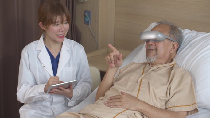 亚洲老年男性患者戴着VR耳机与医生讨论诊断。