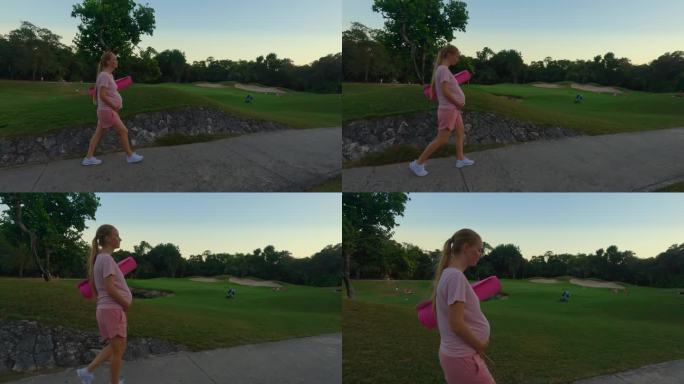 一个令人惊叹的慢动作视频捕捉了一个美丽的母亲时刻。一名孕妇穿着粉色t恤和短裤，手里拿着瑜伽垫，优雅地