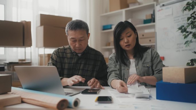 亚洲家族企业主在办公室计算利润，处理收据，工作