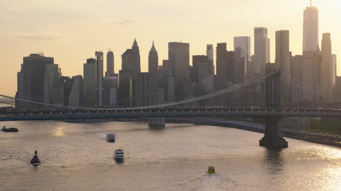 日落时分的纽约天际线。直升机航拍画面。曼哈顿大桥附近的现代摩天大楼。繁忙的大都市，道路和水路都有交通