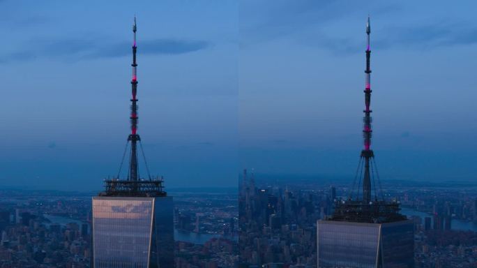 垂直屏幕:带天线的世界贸易中心一号大楼的深夜航拍画面。直升机在玻璃建筑周围飞行，俯瞰纽约市所有五个行