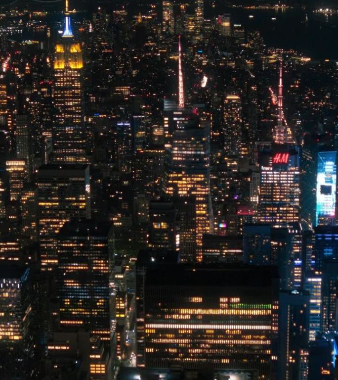 垂直屏幕:晚上的纽约混凝土丛林。直升机之旅的航拍画面。娱乐区和时代广场周围的现代摩天大楼