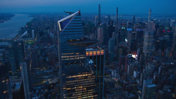 傍晚直升机在曼哈顿天际线上的镜头，聚焦于30哈德逊广场摩天大楼的外部观景台。一群游客在观景台上欣赏城