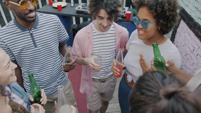 年轻人朋友们在愉快的露天聚会上碰杯喝酒的慢镜头