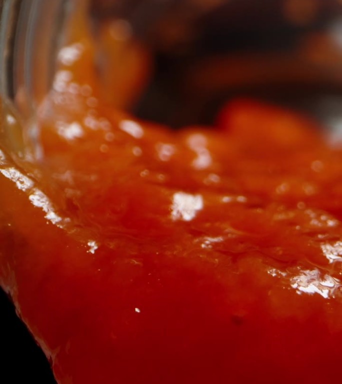 从瓶子里，番茄酱慢慢滴下来，在黑色的背景下，微距变焦。垂直视频。