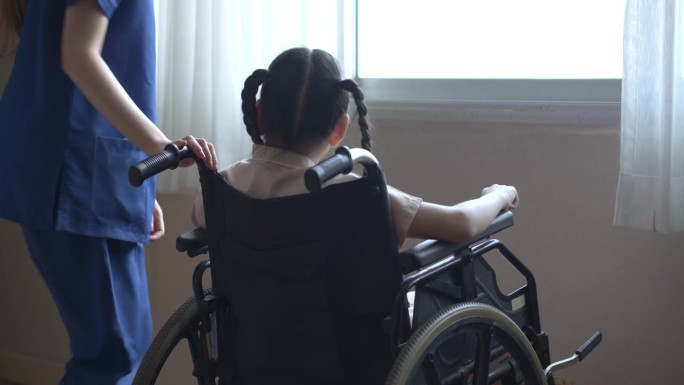 亚洲女护士推着窗边轮椅上的小女孩病人