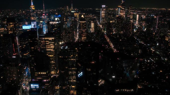 直升机夜游纽约市建筑。飞越曼哈顿，俯瞰灯火通明的办公楼和挤满汽车和出租车的拥挤街道