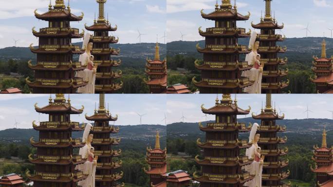 鸟瞰越南的佛教寺庙和雕像，背景是山上旋转的风力涡轮机