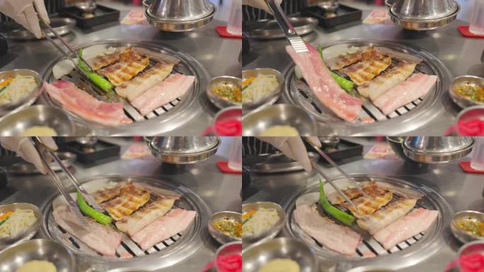 厨师在餐厅的炉子上烧烤肉和猪肉。韩式美食和传统的烧烤风格