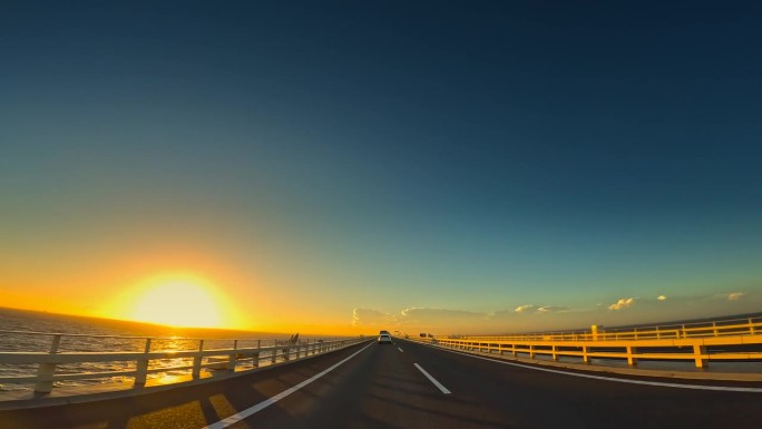 夕阳下行驶在海上高速公路上的汽车