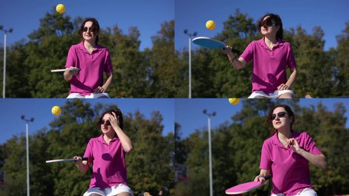 在慢动作视频剪辑中，年轻女子在球场上用球和匹克球桨杂耍