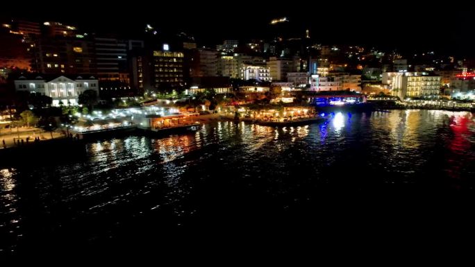 萨兰达灿烂的夜晚:被照亮的长廊在平静的海水上闪烁，展示了沿海城市的夜景之美