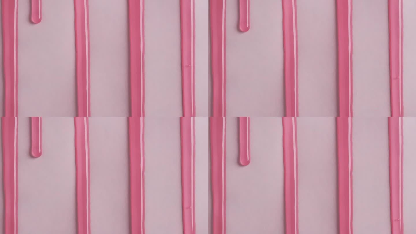 粉红色涂料化妆品的液滴在粉红色的表面流动。粉色沐浴露滴在白色墙上的微距镜头