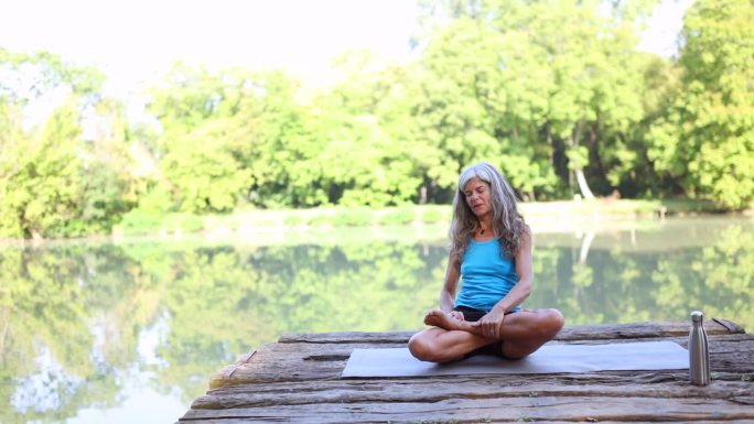 资深女士在湖边练习瑜伽