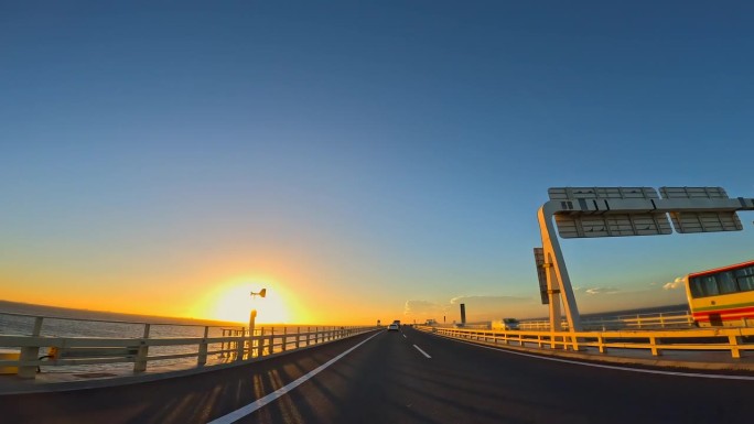 夕阳下行驶在海上高速公路上的汽车