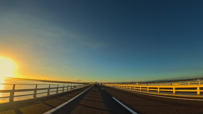 汽车在日出时行驶在海上的高速公路上