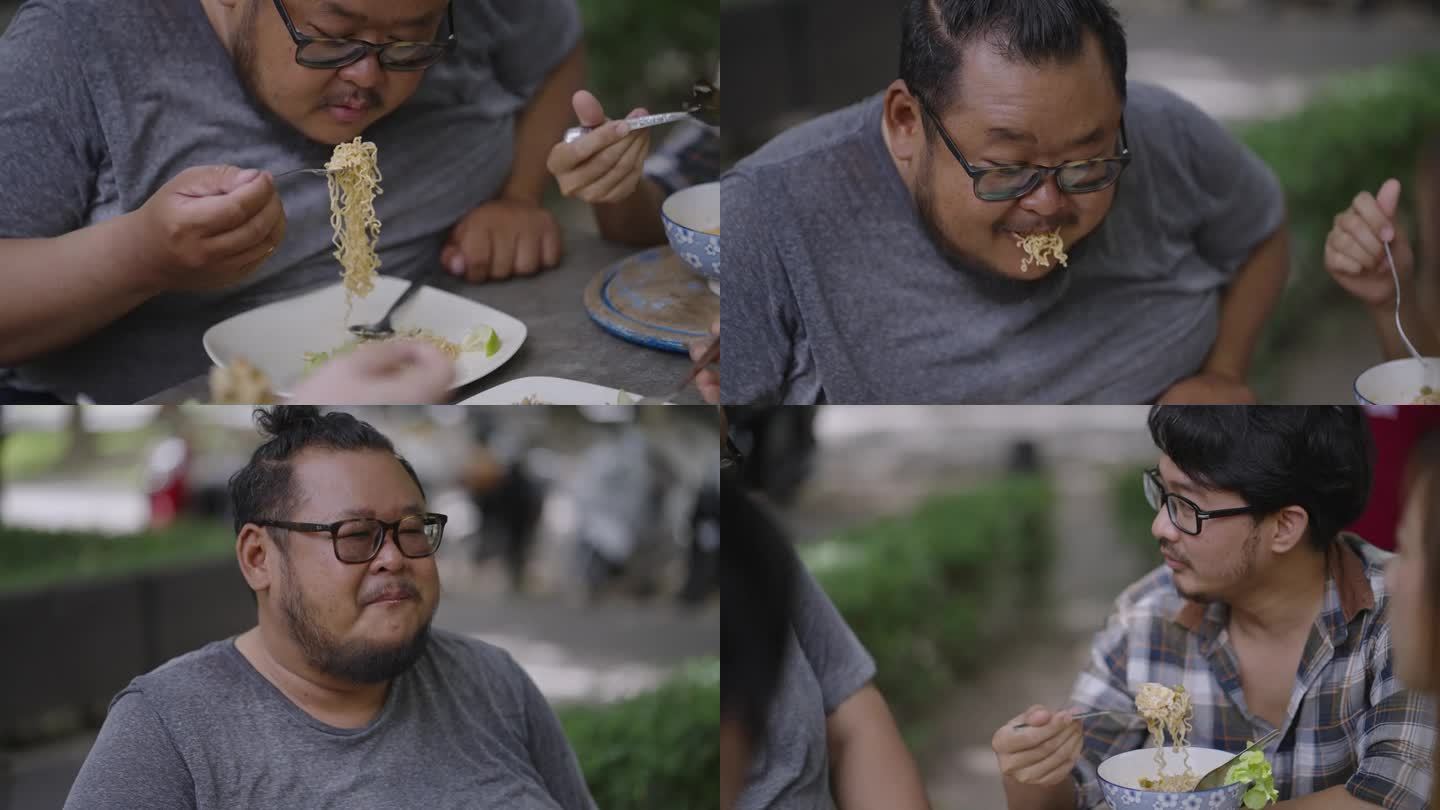 延时:在公园野餐时，一个饥饿的肥胖男子用叉子嚼着一口意大利面，和他的朋友们聊得很开心。
