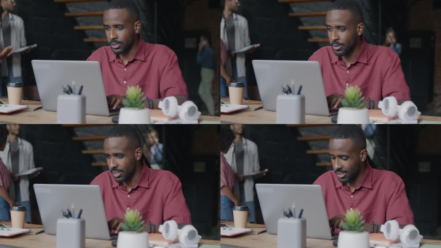 非裔美国员工坐在联合办公中心的办公桌前，使用笔记本电脑在线打字