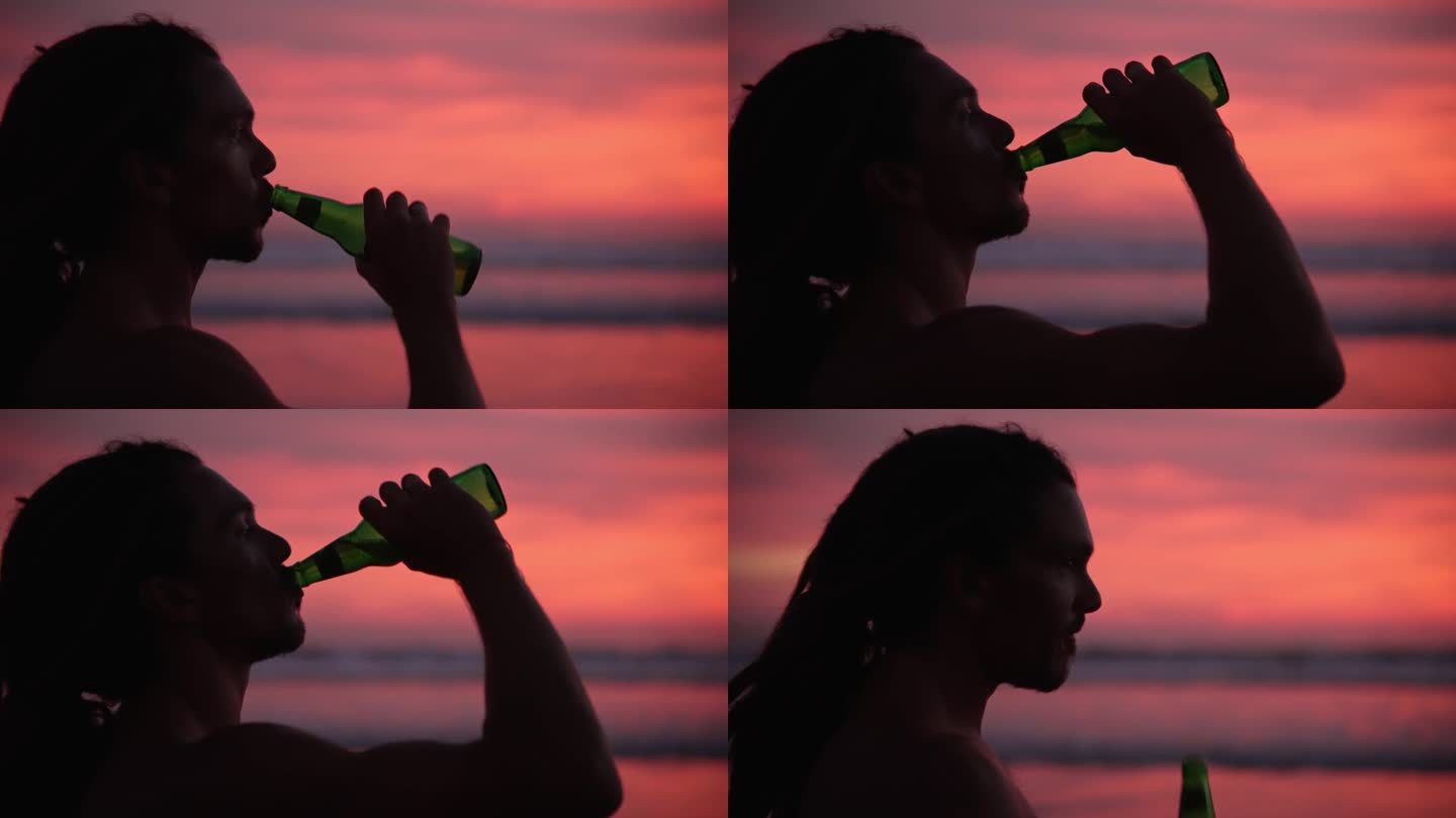 男子在海边或海水的夏日日落边喝啤酒。现代人在假期放松时喝一杯冷饮。在温暖的自然景观的浪漫光线下，热辣