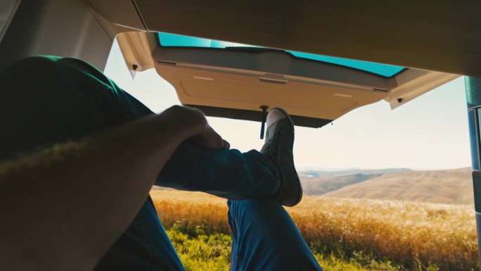 慢动作的视角，男人的腿放松在面包车与农村的视野