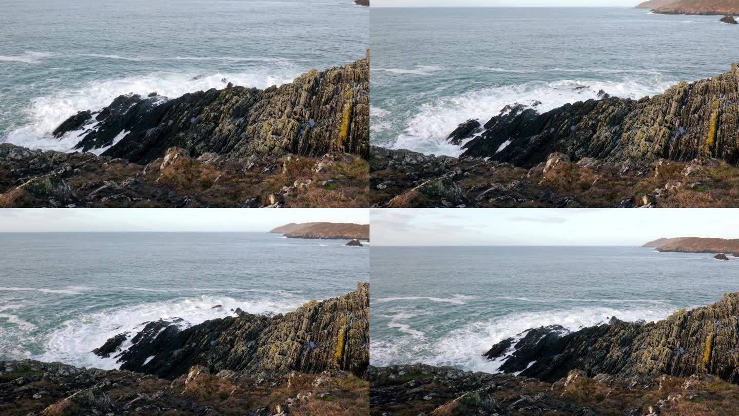 岩石嶙峋的海岸线，锯齿状的岩石在海浪的冲击下屹立不倒。深蓝色的大海，白色的泡沫从波浪。缩小