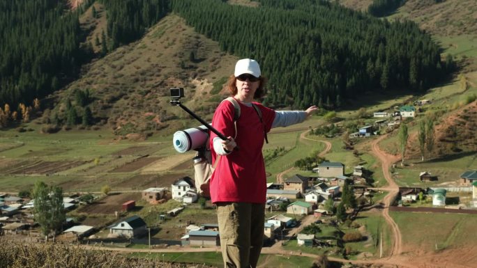 女旅行视频博主站在山谷中的小镇上，讲述着它的故事